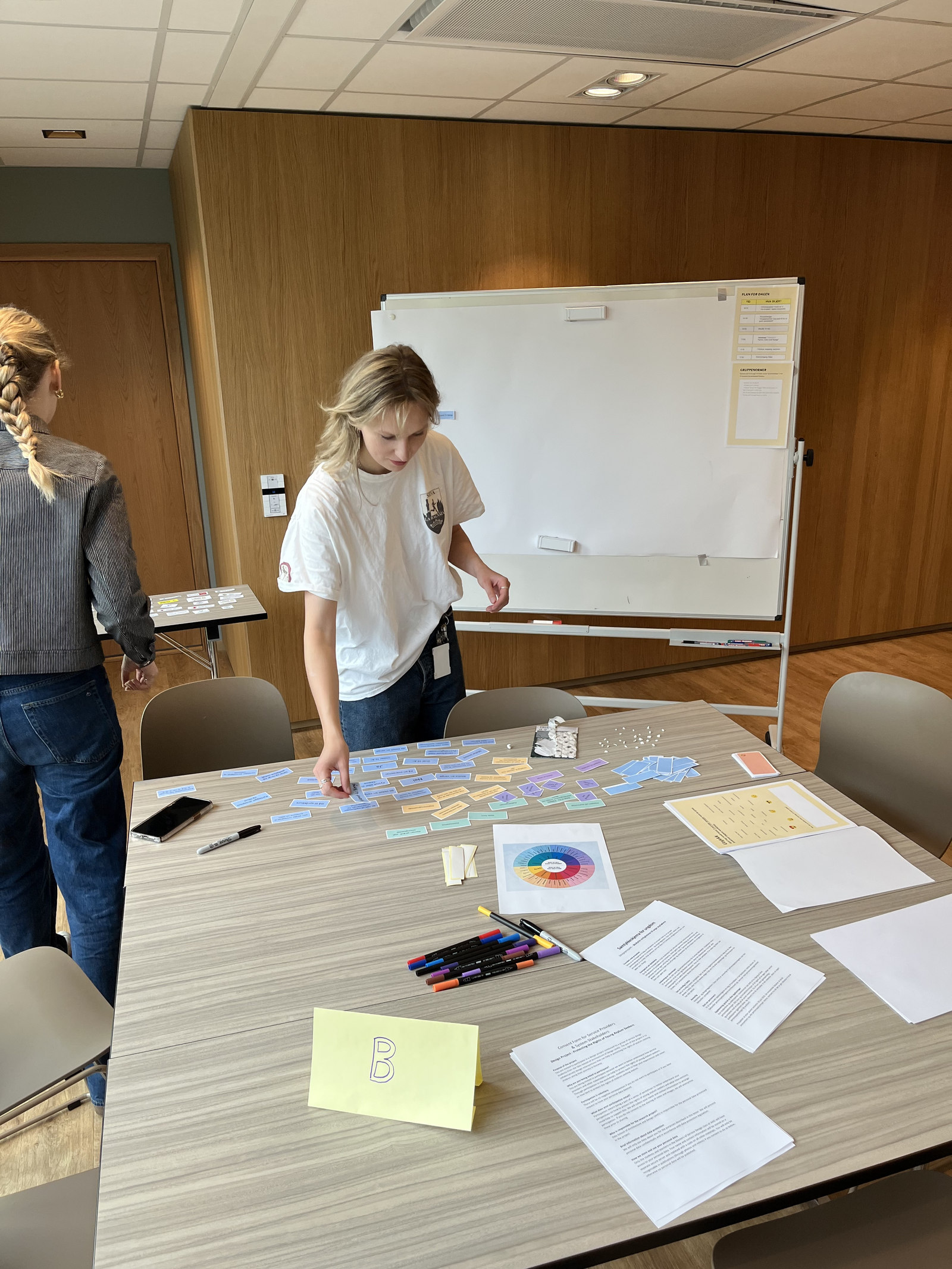 Ingrid legger ut kort på et bord før en co-design-workshop om unge asylsøkeres rettigheter.
