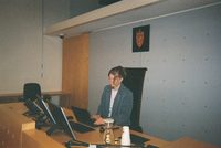En person ved dommerpulten i en tom rettssal.