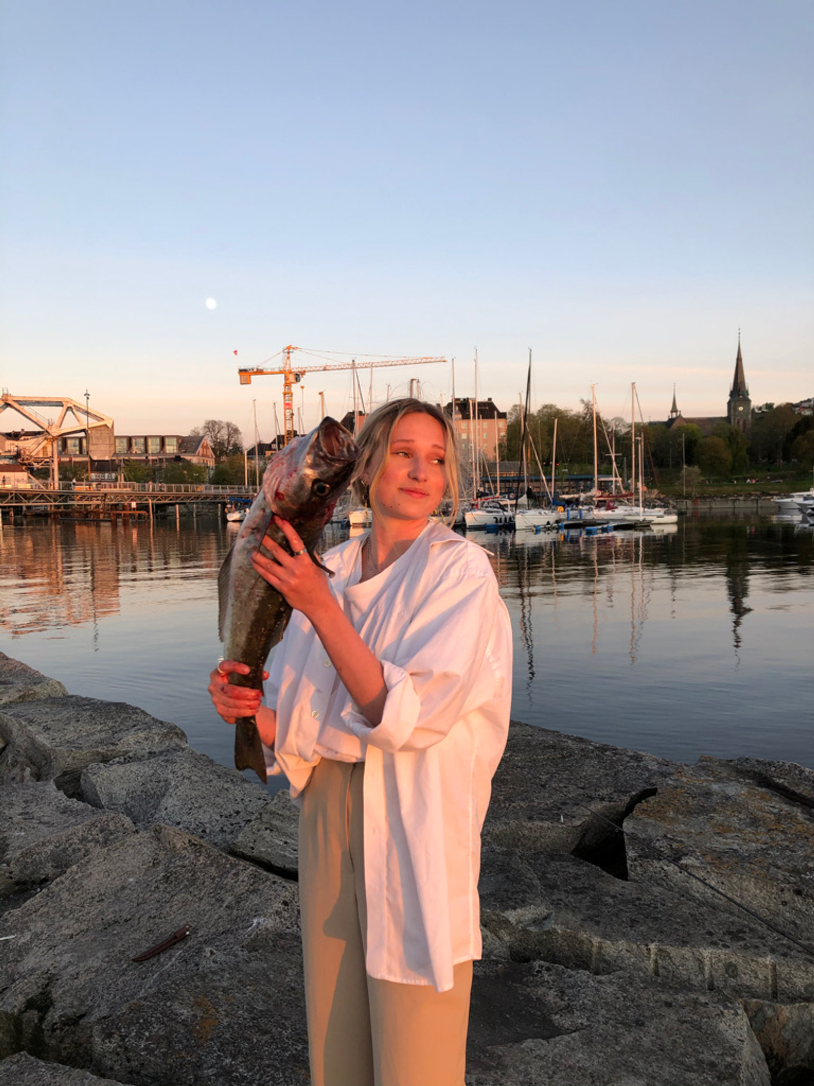 Ingrid med en nyfanget sei ved sjøen.