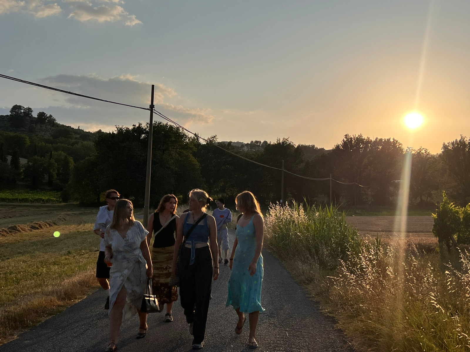 En gruppe går langs en grusvei mellom jorder i Sør-Italia i solnedgang.